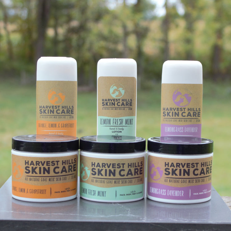 natural goat milk lotions and moisturizers on dark stone with trees in the background