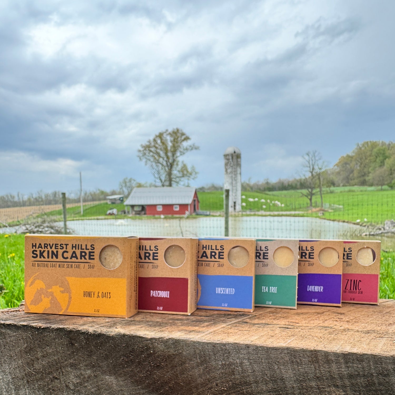 Different types of goat milk soap with farm in background