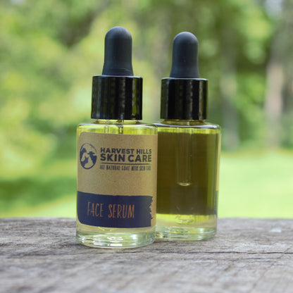 Two bottles of Harvest Hills Skin Care face serum on a wooden surface with a blurred natural background.