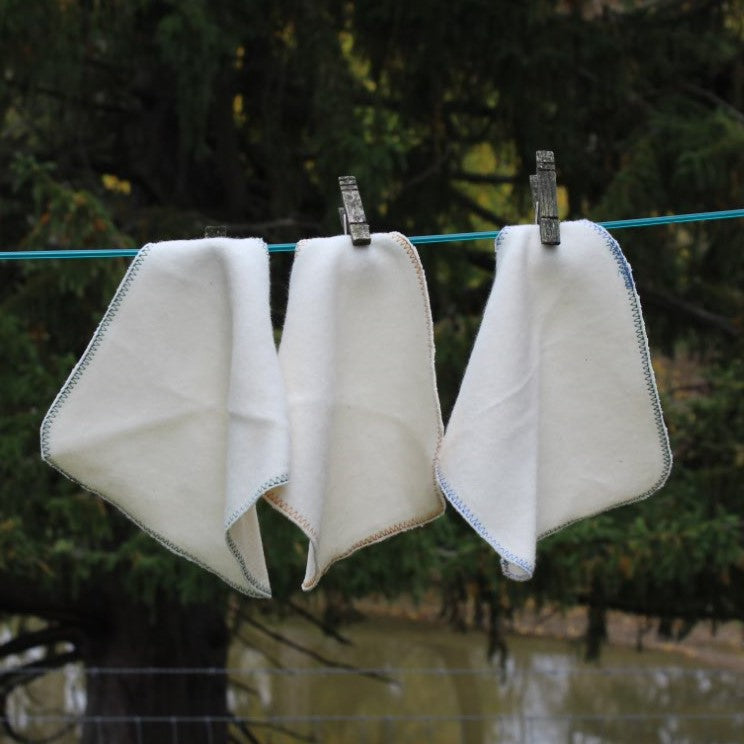 3 organic cotton cloths hanging on a cloths line 