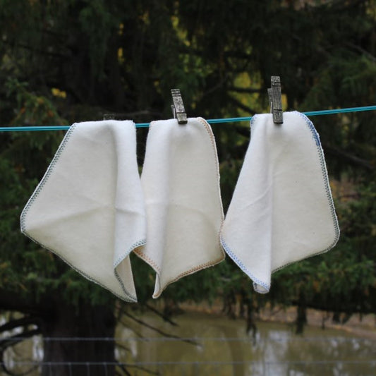 3 organic cotton cloths hanging on a cloths line 