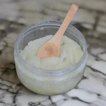 Jar of white cream with a wooden spoon on a rustic wooden surface