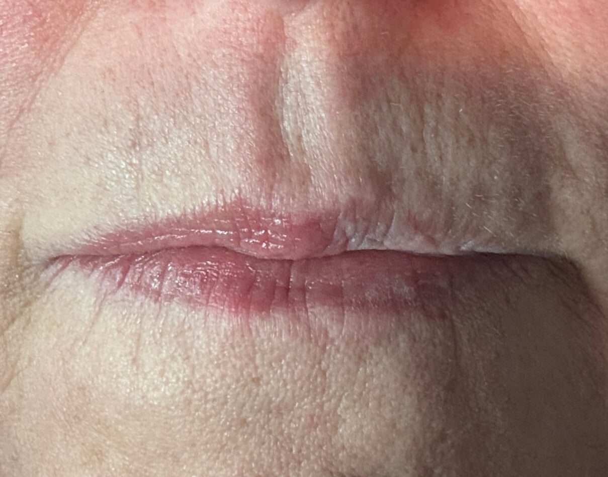 close up of lips with tinted lip balm on half and none on the other half