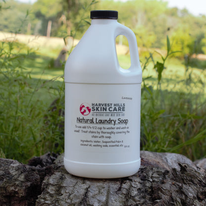 white half gallon jug of natural laundry soap on wood with blurred grass background