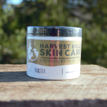 Jar of Harvest Hills Skin Care Vanilla product on a wooden surface with a blurred green background